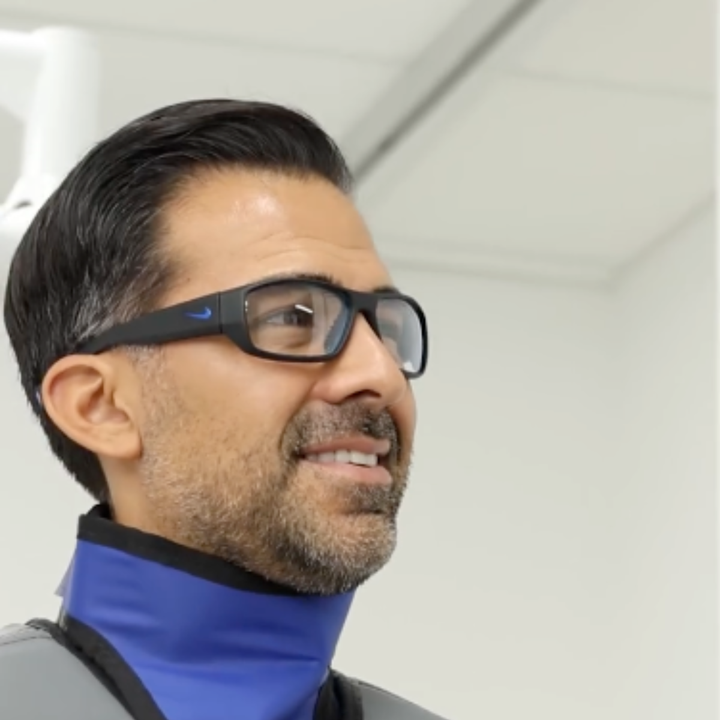 surgeon wearing radiation protection glasses and a blue thyroid collar against a neutral background